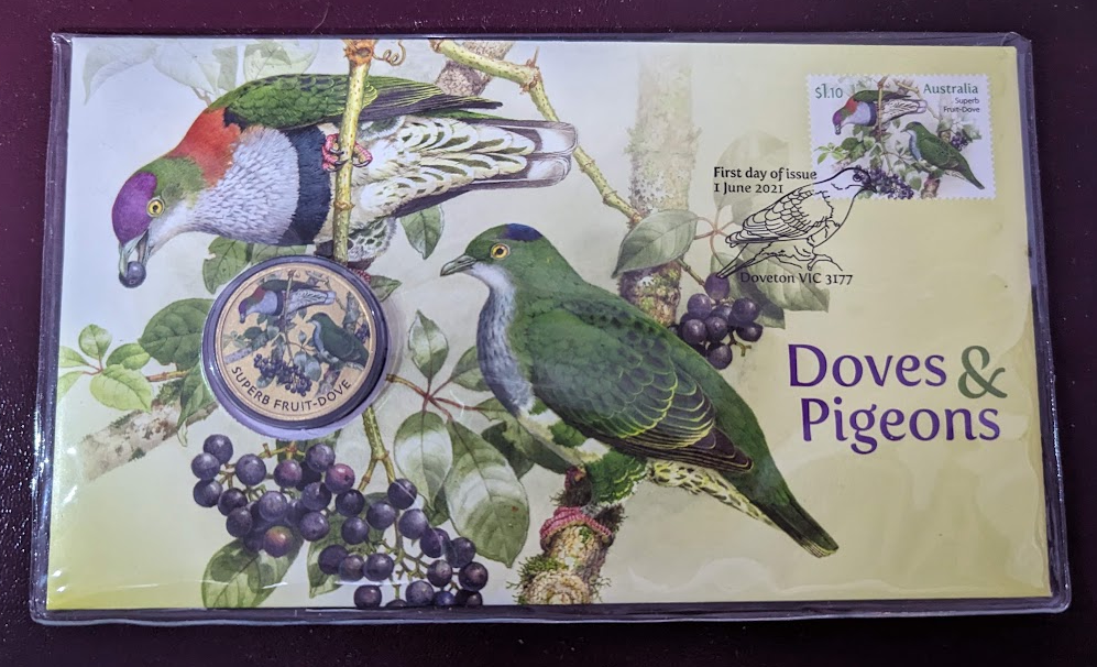 PNC: Envelope with a stamp in the top right, cancelled with a fancy postmark including an image of a dove.  There is a coin embedded in the envelope on the left, and the enveloped is coloured yellow with a large design of fruit doves on branches eating berries.  The same design is also on the stamp and coin