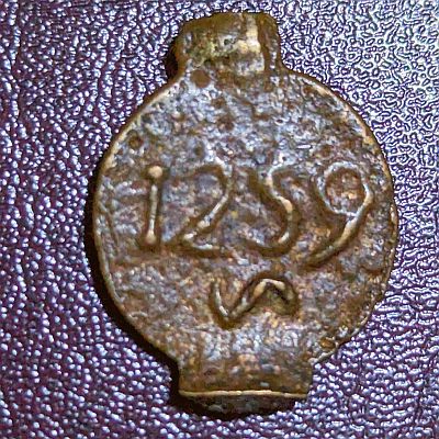 The date "1259" above the mintmark which looks like ~. Two large protrusions top and bottom where coin was originally joined to a "Coin tree"