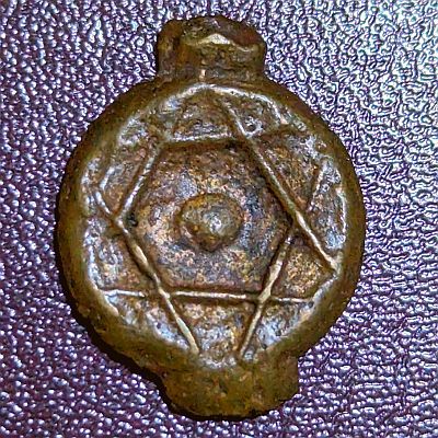 Seal of Solomon design, a six pointed star made up of two equilateral triangles on top of each other with all lines visible. A large dot in the center, and two large protrusions top and bottom where coin was originally joined to a "Coin tree"