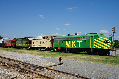 MKT green locomotive with yellow wasp tripes at front with several faded cabooses