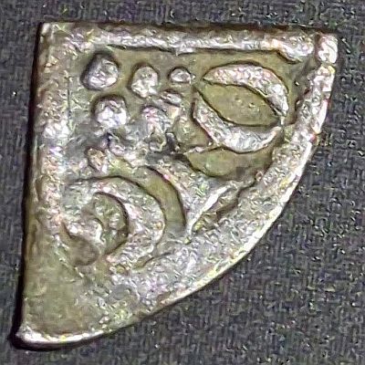 One quarter of a Henry III Long Cross penny cut in quarters showing the long cross, three pellets in the visible quarter and text around edge