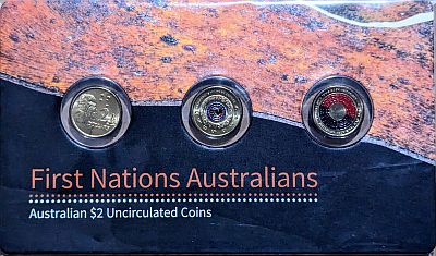 Card with a red rocky landscape top and plain black bottom divided by a white ribbon of track.  Aboriginal Eldar $2 left, Indigenous military service $2 centre and aboriginal flag $2 right.  Text underneath reads First Nations Australians and Australian $2 Uncirculated Coins