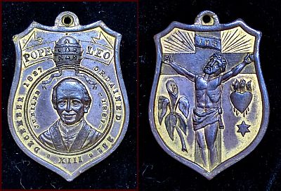 Shield shaped brass medallion with ring on top Obverse: POPE LEO / DECEMBER 1837 (Papal tiara) ORDAINED 23D / JUBILLEE 1887 / (Pope Leo facing forward) / XIII Reverse: (Jesus on cross) HIS / (Lily) (Immaculate heart) / (six pointed star)