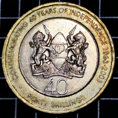 Coat of arms of Kenya, legend on the outer ring. Script: Latin Lettering: · COMMEMORATING 40 YEARS OF INDEPENDENCE 1963-2003 · HARAMBEE 40 FORTY SHILLINGS Translation: All pull together.