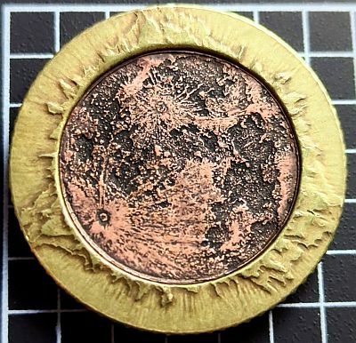 a face of Earth's only moon which is a geographically (technically selenographically) correct 136,794,240:1 scale design of the surface texture of its near side in copper, with the surrounding solar corona struck in brass.