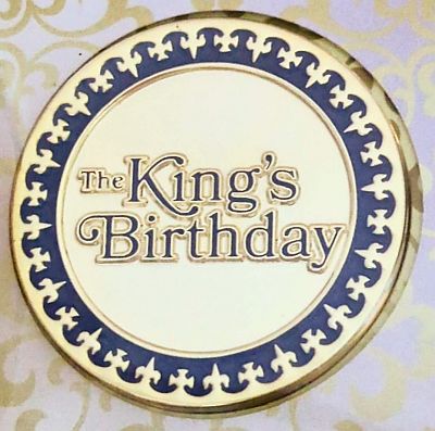 Gold coloured medallion with purple decoration around edge, text: The King's Birthday
