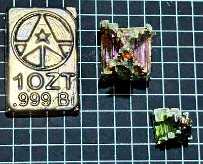Bismuth ingot next to two colourful bismuth crystals