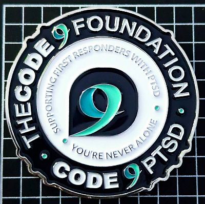 Large round coin with bumps in several places around the edge. THE CODE 9 FOUNDATION above with CODE 9 PTSD below in white on dark blue with the 9 in each being the teal of the logo which is also in the centre. Between, on a white background is "SUPPORTING FIRST RESPONDERS WITH PTSD and YOU'RE NEVER ALONE