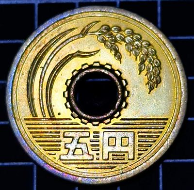 Reverse Large bending stalk of rice representing agriculture on top, water with value at the bottom representing fisheries, and teeth of a cog around the central hole representing industry Lettering: 五円 Translation: 5 yen